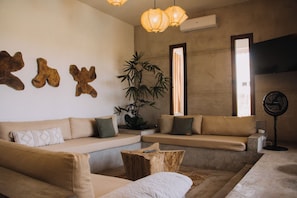 A modern living room with a sectional sofa, a coffee table, and a large plant.