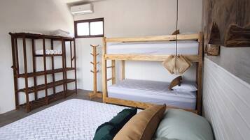 A room with a bunk bed, a ceiling fan, a wooden shelf, and a wall-mounted light fixture.
