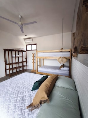 A room with a bunk bed, a ceiling fan, a wooden shelf, and a wall-mounted light fixture.