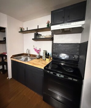 Cozinha com fogão preto, pia e bancadas de madeira.
