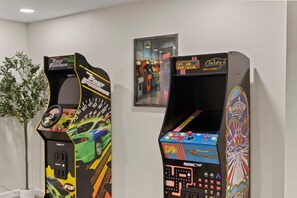 Two arcade machines with colorful graphics and controls, placed in a room with a white wall and a framed picture above them. - Pool, Hot Tub, Pickleball, Sauna, Game Room, Basketball, Fire Pit & Kids Playset (Columbus)