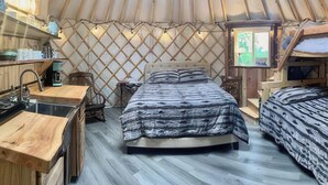 A cozy yurt interior with a bed, a small table, and a television. - A cozy yurt with all of the amenities (Big Lake)