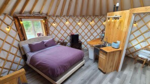 A yurt interior with a bed, desk, and kitchenette. - A cozy yurt with all of the amenities (Big Lake)