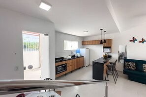 A modern kitchen with wooden cabinets, a black countertop, and a built-in oven. - Apartamento 4 com 2 suítes 450m da praia (Santa Cruz Cabrália)