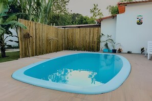 A swimming pool with a wooden fence and potted plants. - Apartamento 4 com 2 suítes 450m da praia (Santa Cruz Cabrália)