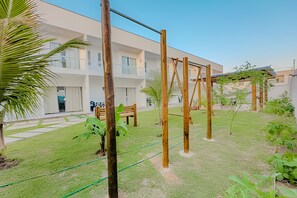Ein Innenhof mit einer Holzschaukel, einer Bank und einem Gebäude mit großen Fenstern im Hintergrund.