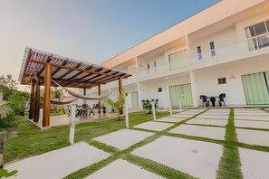 Un bâtiment moderne doté d’un espace extérieur couvert avec des sièges et d’une cour intérieure agrémentée d’un chemin décoratif.