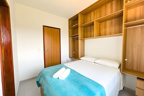 A bedroom with a bed, a wardrobe, and a door. - Apartamento 4 com 2 suítes 450m da praia (Santa Cruz Cabrália)