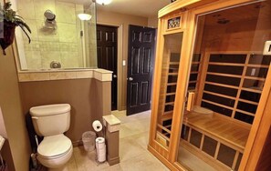 Un baño con inodoro, ducha y recinto de sauna de madera.