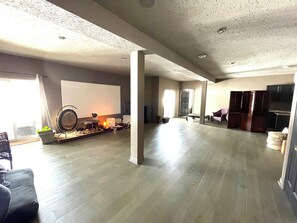 A spacious living room with a fireplace, a flat-screen TV, and a large window.