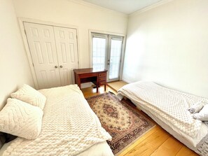A bedroom with a double bed, a single bed, a desk, and a door.
