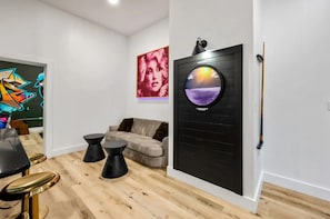 A modern living room with a sofa, a round wall-mounted TV, and a painting on the wall.