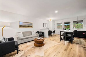 A modern living room with a sofa, a coffee table, and a dining area with chairs.