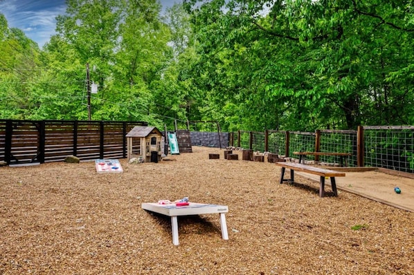 An outdoor play area with a wooden bench, a small table, and a fenced enclosure.