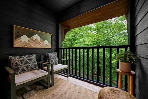 A porch with a bench, a painting, and a potted plant.
