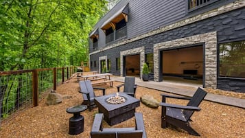A modern house with a stone facade, outdoor seating, and a fire pit.
