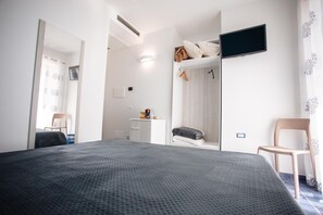 Una camera da letto con un letto, una TV a parete, una sedia e un armadio.
