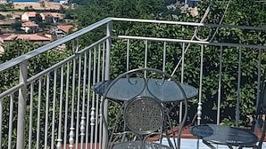 Un balcone con una sedia e un tavolo in metallo, affacciato su un paesaggio costiero con case e barche.