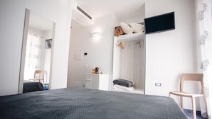 Una camera da letto con un letto, una TV a parete, una sedia e un armadio.
