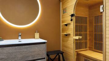 Ein modernes Badezimmer mit rundem Spiegel, Waschtisch aus Holz und einer Sauna-Bereich.