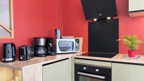 Una cocina compacta con microondas, cafetera, tostadora y horno pequeño.