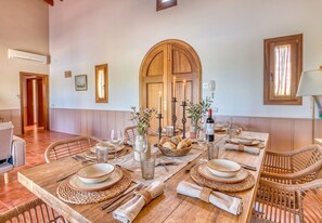 A dining room with a long wooden table set for a meal, surrounded by wicker chairs. - Finca with pool Son Crestes, Sa Pobla (Sa Pobla)