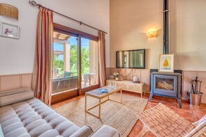 A living room with a sofa, a table with books, a fireplace, and a television. - Finca with pool Son Crestes, Sa Pobla (Sa Pobla)