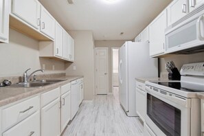 A kitchen with white cabinets, a stainless steel sink, a refrigerator, and a stove. - Misty Lane Retreat | Walk to Parks & Disc Golf (Ashland)