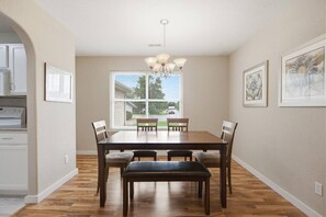 A dining room with a wooden table, six chairs, a chandelier, and artwork on the walls. - Misty Lane Retreat | Walk to Parks & Disc Golf (Ashland)