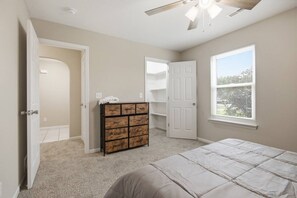 Une chambre à coucher avec un lit, une commode, un placard et une fenêtre.