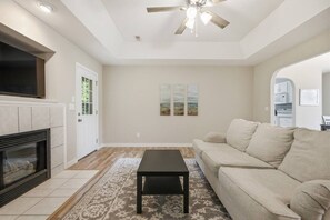 A living room with a fireplace, a ceiling fan, a sofa, and a coffee table. - Misty Lane Retreat | Walk to Parks & Disc Golf (Ashland)