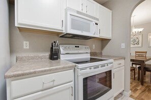 A kitchen with white cabinetry, a built-in microwave, a stove, and a knife block. - Misty Lane Retreat | Walk to Parks & Disc Golf (Ashland)