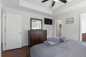A bedroom with a bed, a dresser, a television, and a framed picture on the wall. - Penny Lane Retreat | 15 Min. to Stadium (Columbia)