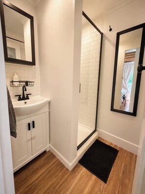 Un bagno con un lavandino bianco, un rubinetto nero e uno specchio con cornice nera.