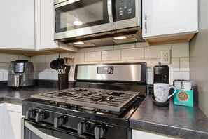 A kitchen with a gas stove, a microwave, a coffee maker, and a box of coffee pods. - Raven`s House - Fence, Garage | 10 Min. to Stadium (Columbia)