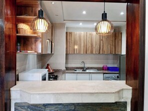 Una cocina moderna con armarios de madera, encimera blanca e iluminación colgante.