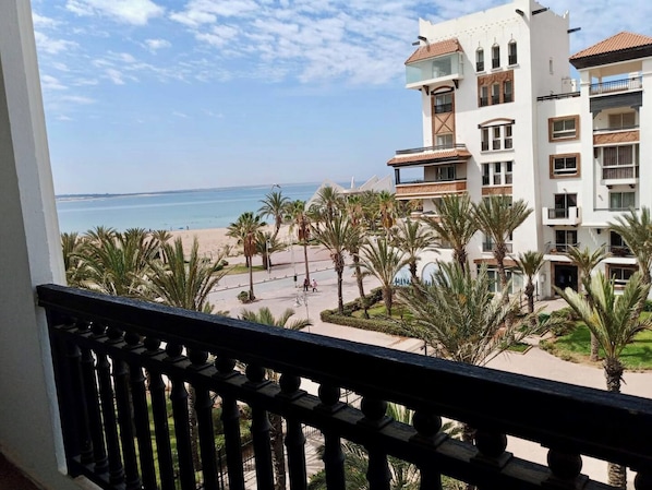 A hotel with multiple floors, a beach view, and palm trees.
