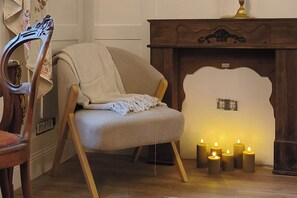 A cozy room with a wooden chair, a fireplace with lit candles, and a decorative wall piece. - Chateau Suite Ernestine (Malberg)