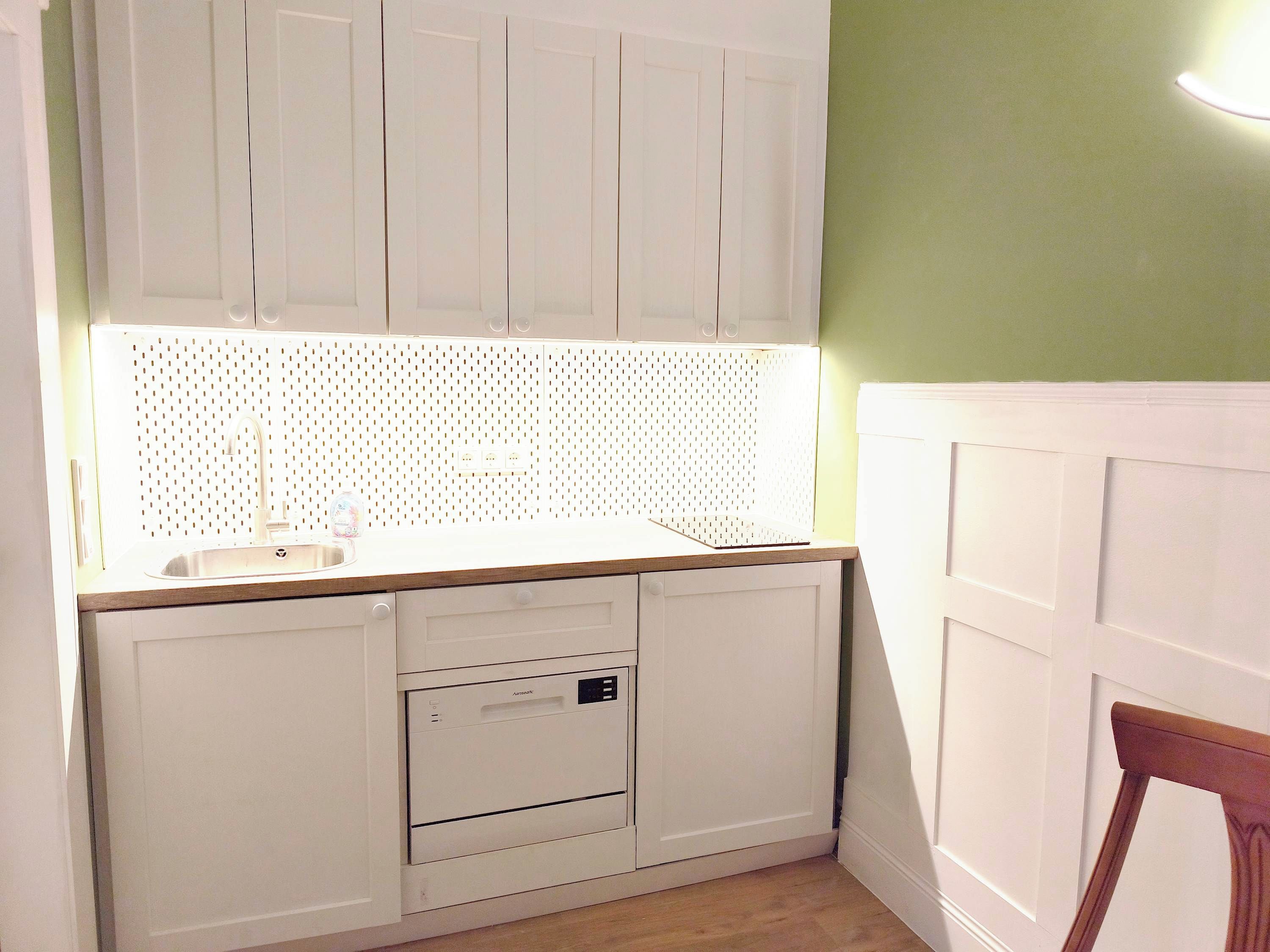 A kitchen with white cabinets, a wooden countertop, and a built-in dishwasher.