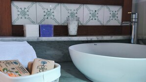 Un baño con una bañera blanca grande, un lavamanos blanco con artículos de aseo y un salpicadero decorado con azulejos.