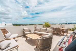 Eine Dachterrasse mit Gartenmöbeln, darunter eine Sitzecke mit Sofa, Stühlen und einem Tisch.