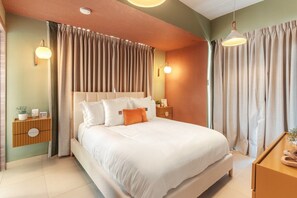 Quarto com cama grande, mesas de cabeceira e cortinas.