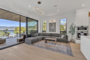 Ein modernes Wohnzimmer mit einer Eckcouch, einem Couchtisch und Blick aufs Meer.