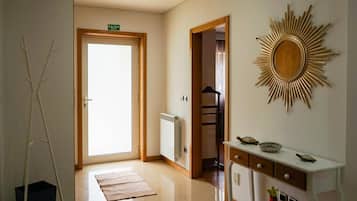 A hotel hallway with a radiator, a sunburst wall decoration, a door marked 'SAIDA EXIT', and a small table with decorative items.