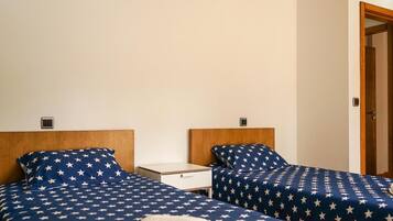 A hotel room with two beds, each with a headboard and a nightstand.