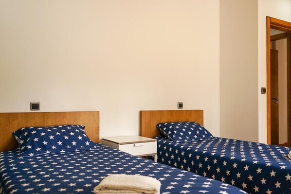 A hotel room with two beds, each with a headboard and a nightstand.