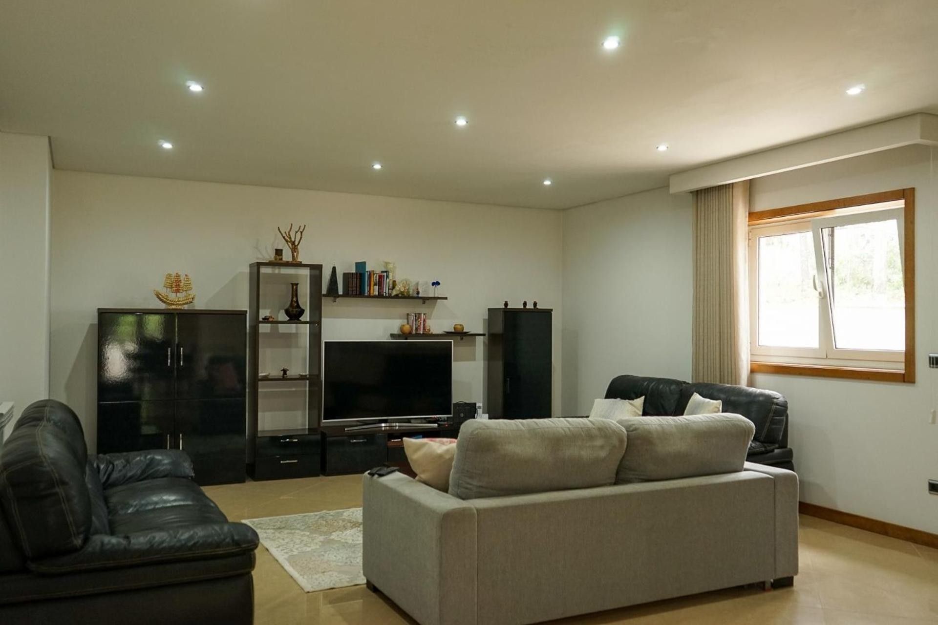 Un salon avec un canapé, un téléviseur et un meuble.