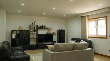 Un salon avec un canapé, un téléviseur et un meuble.