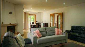 A living room with a fireplace, a sofa, a coffee table, and a dining area with a table and chairs.