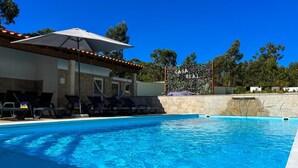 Una piscina con sillas de descanso y una pérgola con sombrilla.